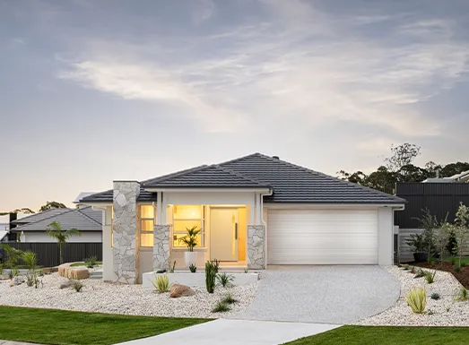 Modern single-story house with white rendered walls and dark grey roof, featuring a curved design, illuminated entrance, white garage door, and landscaped front yard with gravel and native plants at dusk.