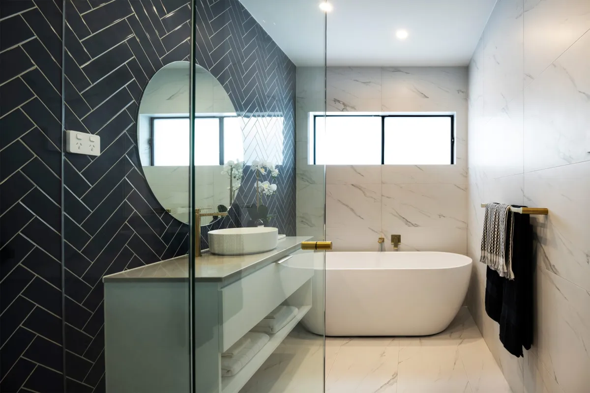 classic white freestanding bath with gold tapware and backed by marble walls