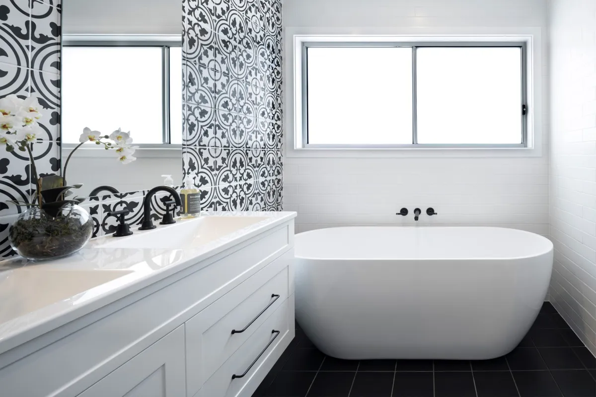 freestanding, oval-shaped bath next to an intricately patterned tile feature wall