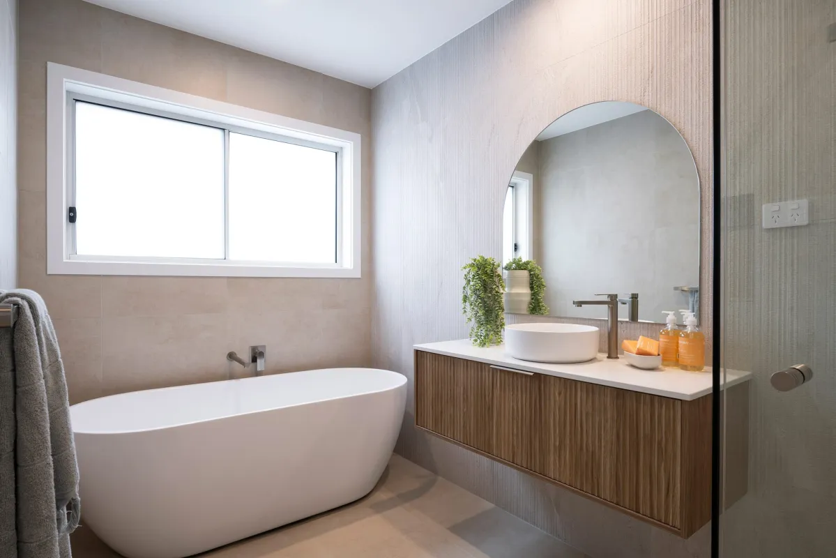 Coastal-style bathroom with oval freestanding bath, plant life, and timber elements