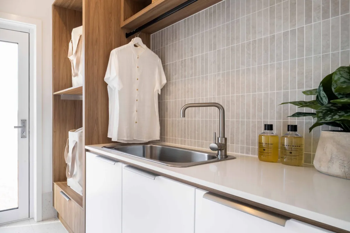 Hamptons-style laundry with clever storage options and a mix of timber, cream, and white accents