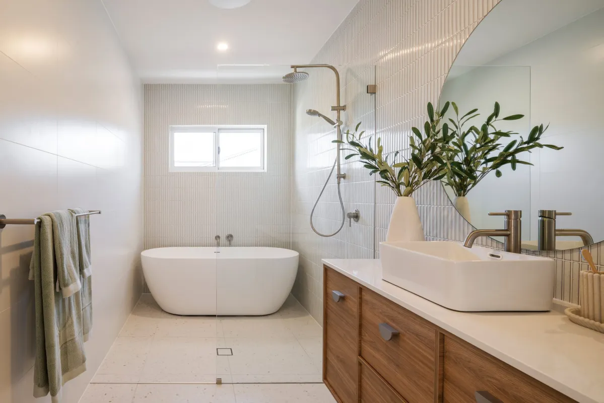 Hamptons-style bathroom with textured, cream-coloured tiling, timber cabinetry, and chrome tapware