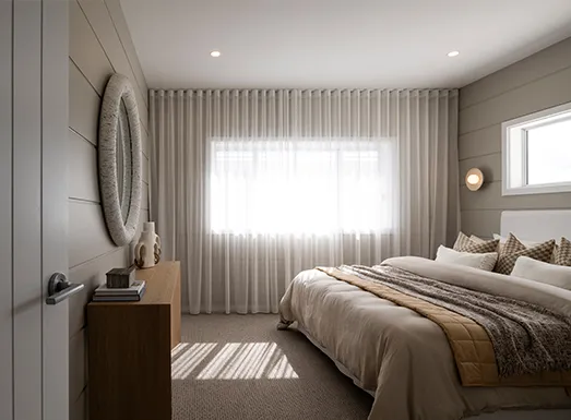 Modern bedroom with neutral beige and gray tones, featuring a bed with cream bedding and decorative pillows, floor-to-ceiling sheer curtains covering large windows, a round wall mirror above a dark wooden nightstand, recessed ceiling lights, and neutral carpeting.