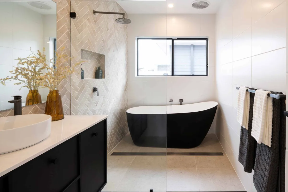 monochrome-themed freestanding bath placed under an open window