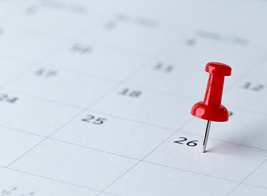 Red pushpin marking date 26 on a calendar page, representing a scheduled demolition date.