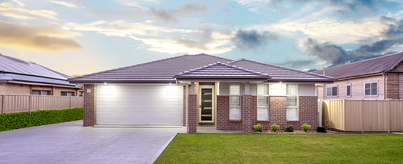 Modern single-story brick house with white garage door, dark roof, and manicured front lawn at dusk in Cardiff.